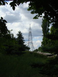 Low angle view of tower and trees on field against sky