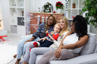 Mother and daughter sitting on sofa at home