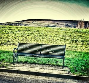 Empty bench on grassy field