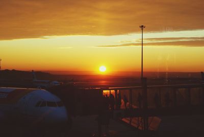 Airplane on runway against sky during sunset