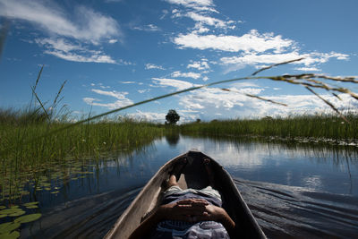 Men relaxing in boat on lake by grass