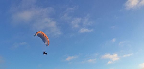 Low angle view of person paragliding against sky