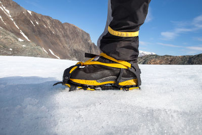 Low section of male hiker wearing crampon while ice climbing at lyngen alps