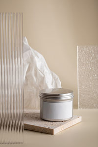 Simple composition with face cream in a metal jar on a beige background with stone and glass