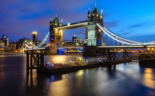 Illuminated suspension bridge over river at night