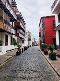 Surface level of footpath amidst houses against sky