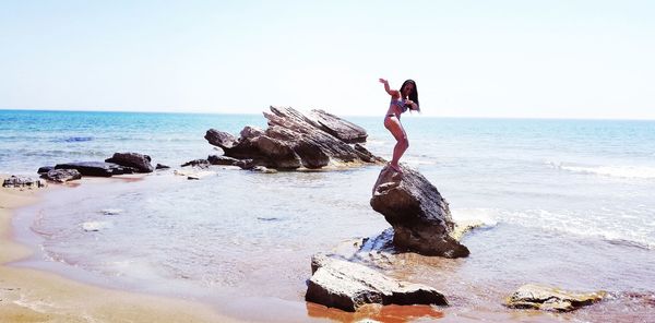 Full length of man on rock at beach against sky