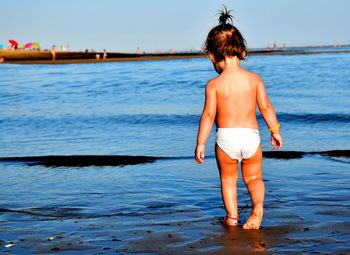 Rear view of toddler standing at beach