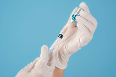 Midsection of person holding hands against blue background