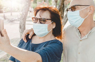 Senior couple wearing mask doing selfie outdoors