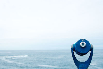 Close-up of coin-operated binoculars against sea