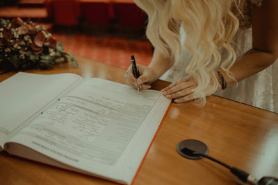 Midsection of woman reading book while sitting on table