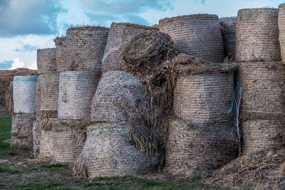 Stack of hay bales on field against sky