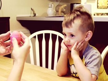 Portrait of cute boy sitting on table