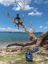 Man jumping on beach against sky
