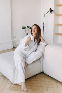 Young woman using mobile phone while sitting on sofa at home