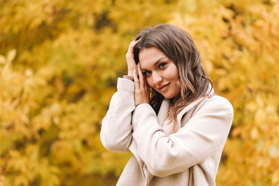 A beautiful happy girl in casual clothes is walking in the autumn outdoor park drinking coffee