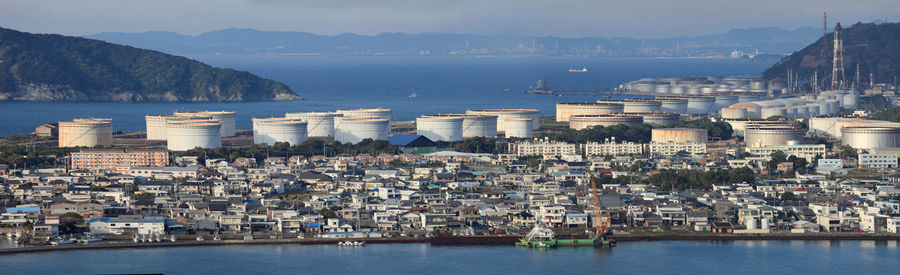 Aerial view of city by sea against sky