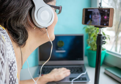 An elderly woman wearing headphones .