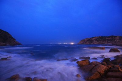 Scenic view of sea and rocks against clear blue sky