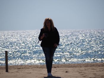 Full length of woman standing on beach against sky