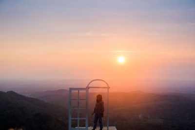 People standing on mountain against sky during sunset