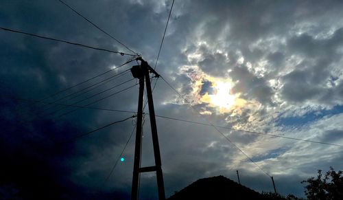 Low angle view of silhouette electricity pylon against sky during sunset