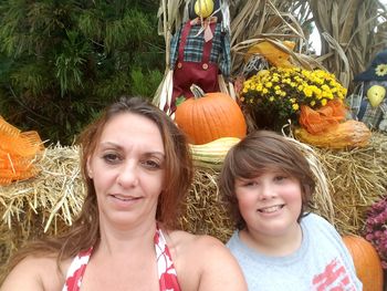 Portrait of smiling mother with son sitting by halloween decoration