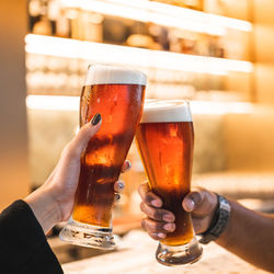 Cropped hand of woman holding beer glass