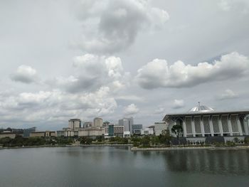 Buildings by river against sky in city