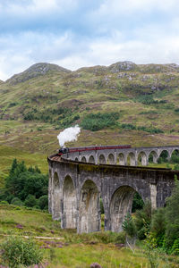 Arch bridge over landscape against sky