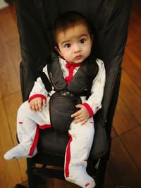 Portrait of cute baby boy sitting in stroller at home