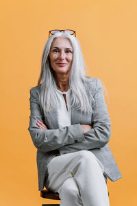 Portrait of young woman against yellow background