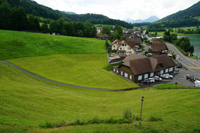 Scenic view of grassy field and houses against mountains