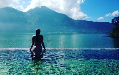 Rear view of woman at infinity pool against mountain