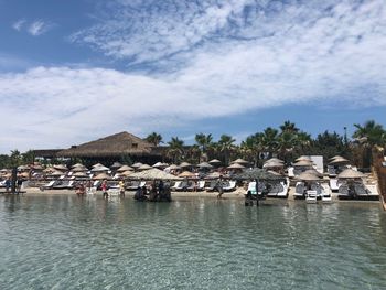 Houses by river and buildings in town against sky