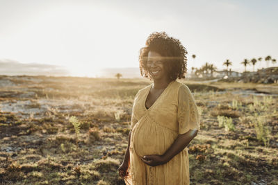 Portrait of pregnant mother in third trimester at beach at sunset