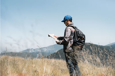 Man hiking on field against mountains