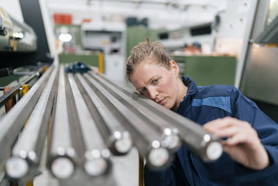 Young woman working as a skilled worker in a high tech company, checking steel rods