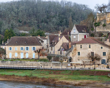 Houses on field by river against buildings