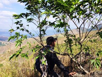 Man with lizard on landscape against clear sky