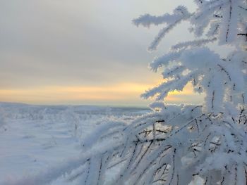 Snow covered landscape against sky during sunset