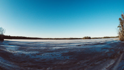 Scenic view of snow covered land against clear blue sky