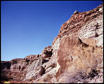 Low angle view of rock formations against clear blue sky