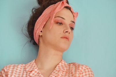 Close-up portrait of young woman against blue background