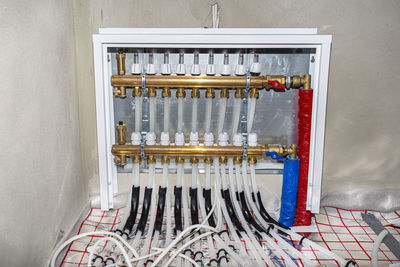 New manifold of underfloor heating system, plastic pipes and valves visible, serving nine circuits.