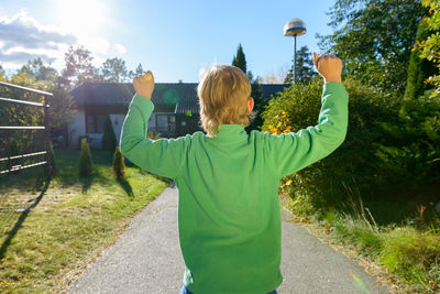 Rear view of woman standing by road against sky