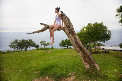 Full length of young woman jumping on tree