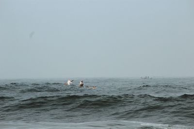 Men in sea against clear sky