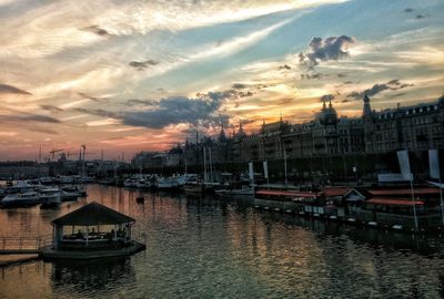 Boats at harbor against cloudy sky